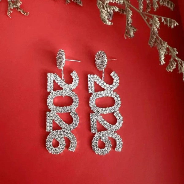 Rhinestone 2026 earrings on a red background with decorative elements