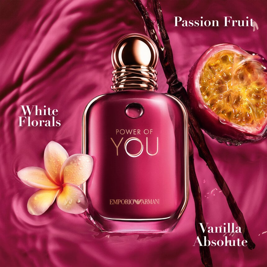 Pink Emporio Armani perfume bottle with floral and fruit elements on a pink background