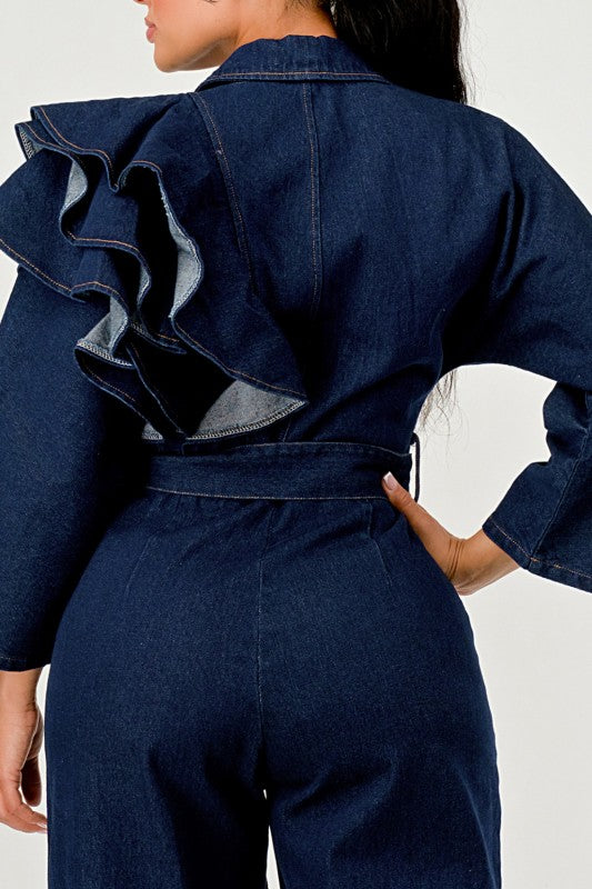 Person wearing a blue denim outfit with ruffled details on a white background