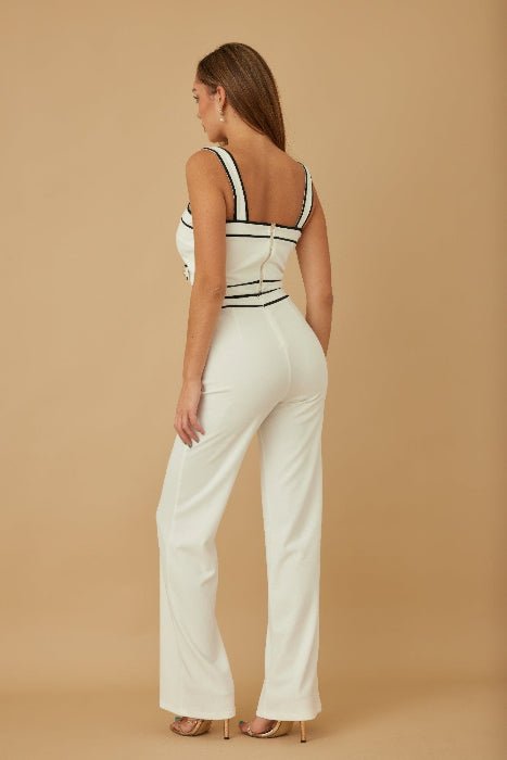 Woman wearing a white jumpsuit with black accents on a beige background