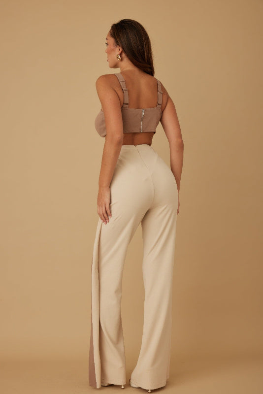 back view of a Woman wearing a beige top and wide-leg pants against a beige background