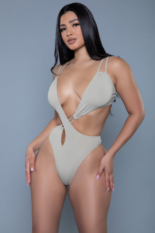 Woman wearing a beige swimsuit against a gray background