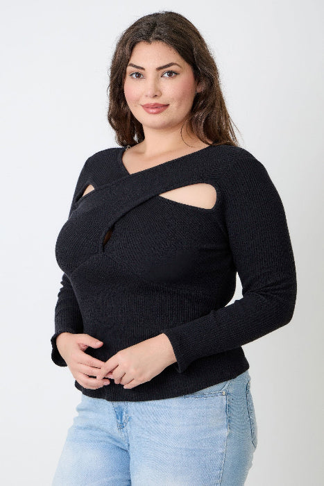 Woman wearing a black cut-out sweater and light blue jeans against a white background