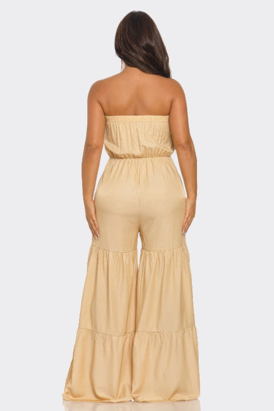 back view of Woman wearing a beige strapless jumpsuit on a white background