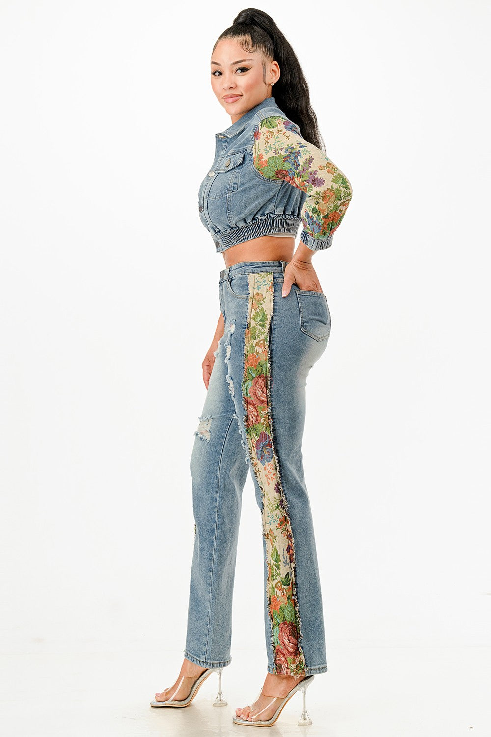 Woman wearing a denim outfit with floral patterns on a white background