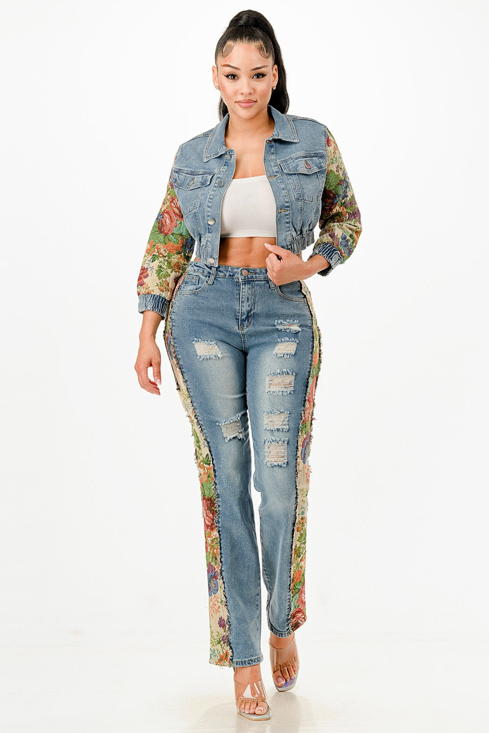 Woman wearing a floral jacket, white top, and distressed jeans on a white background