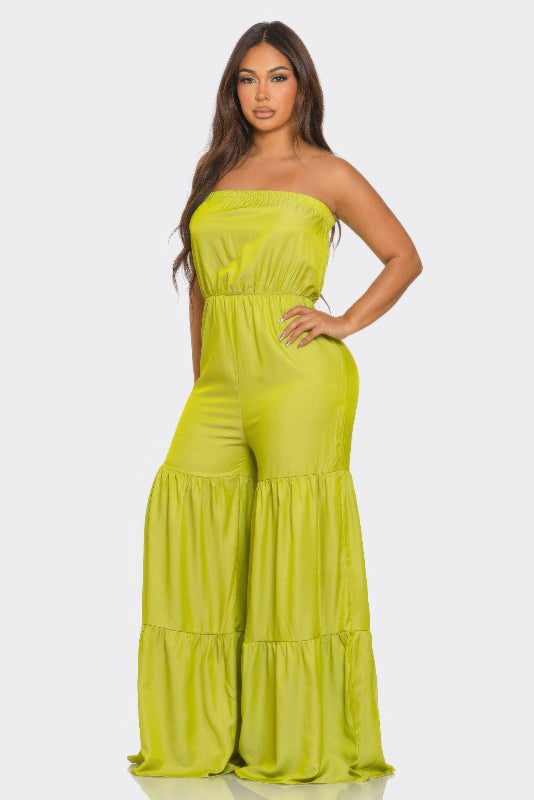 Woman wearing a bright green strapless jumpsuit on a white background