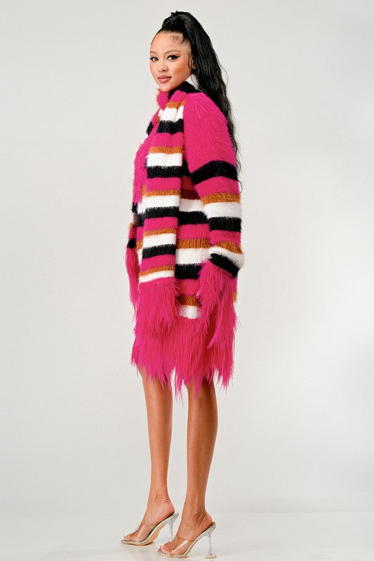 Woman wearing a bright pink and multicolor striped scarf with fringe on a white background
