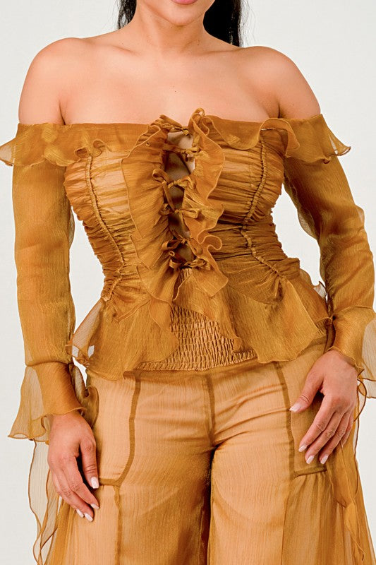 Woman wearing a mustard yellow off-shoulder top and pants on a white background