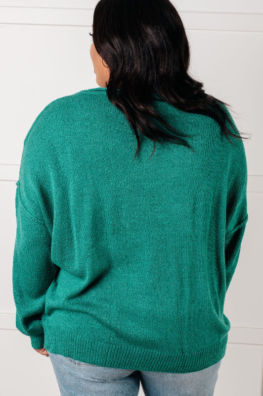Person wearing a teal sweater with a white background