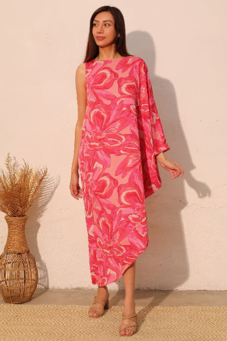 Woman wearing a pink floral dress standing against a white wall.