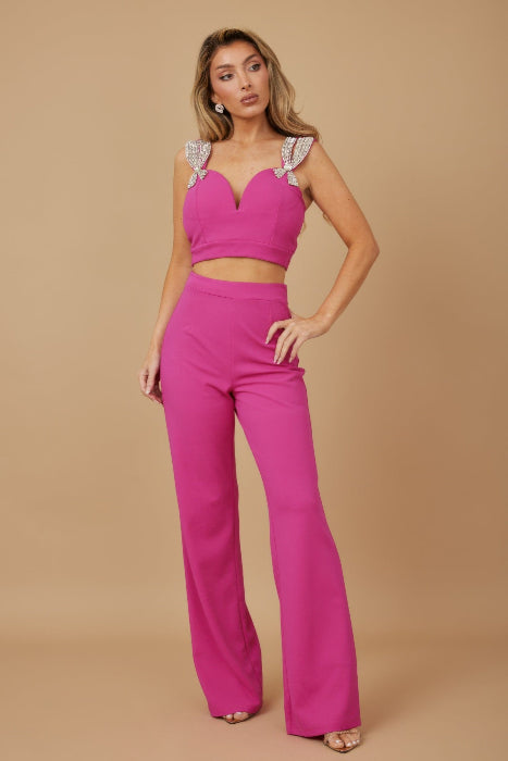 Woman wearing a pink outfit with jewel details on a beige background