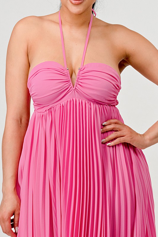 close up of Pink halter neck dress worn by a woman on a plain background