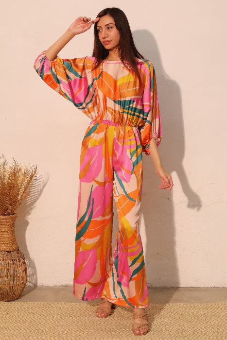 Woman wearing a colorful pink patterned jumpsuit against a plain background