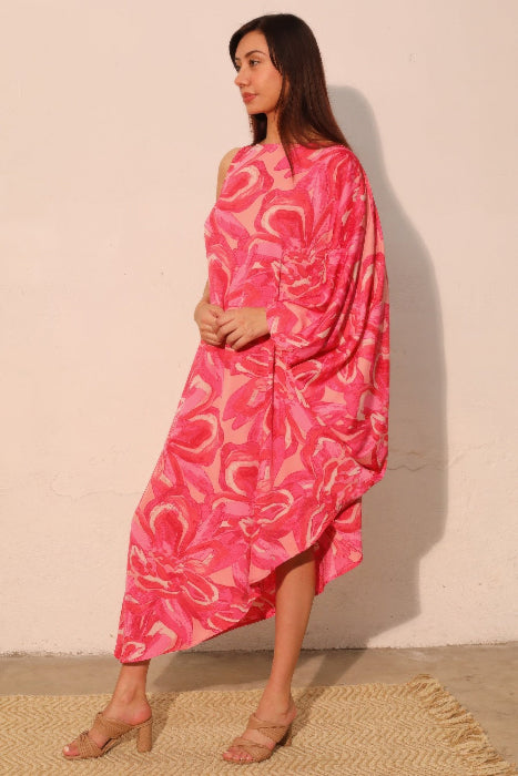 Woman wearing a pink patterned dress against a beige wall.