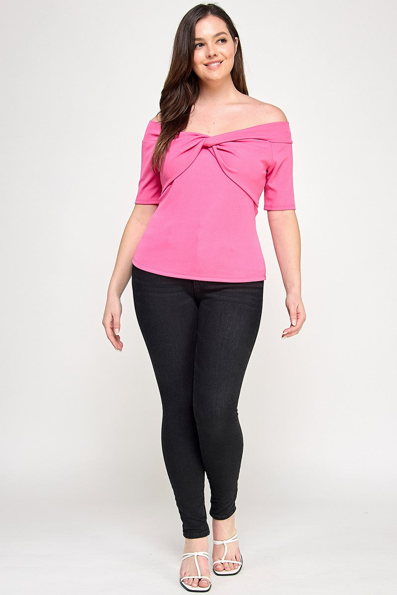 Woman wearing a pink off-shoulder top and black leggings on a white background