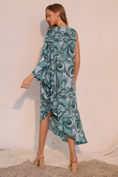 Woman wearing a blue and green patterned dress against a white background back view