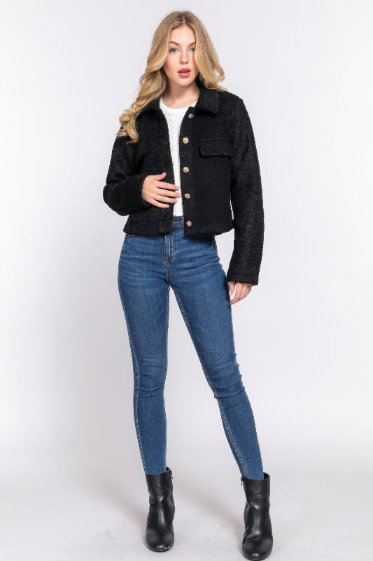 Woman wearing a black jacket, white shirt, blue jeans, and black boots on a white background