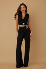 Woman wearing a black pant suit on a beige background