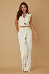 Woman wearing a white outfit with gold accents on a beige background