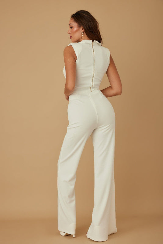 Woman wearing a white pant suit against a beige background