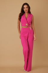 Woman wearing a pink pant suit with gold accents on a beige background