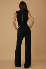 Woman wearing a black sleeveless pant set on a beige background