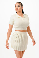 Woman wearing a cream-colored polo shirt and pleated skirt on a white background