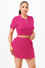 Woman wearing a bright pink polo shirt and pleated skirt on a white background
