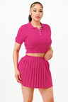 Woman wearing a bright pink polo shirt and pleated skirt on a white background