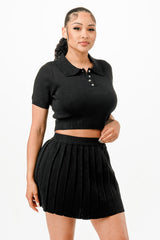 Woman wearing a black polo shirt and black pleated skirt on a white background