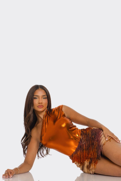Woman in a shiny orange skirt set posing on a white background