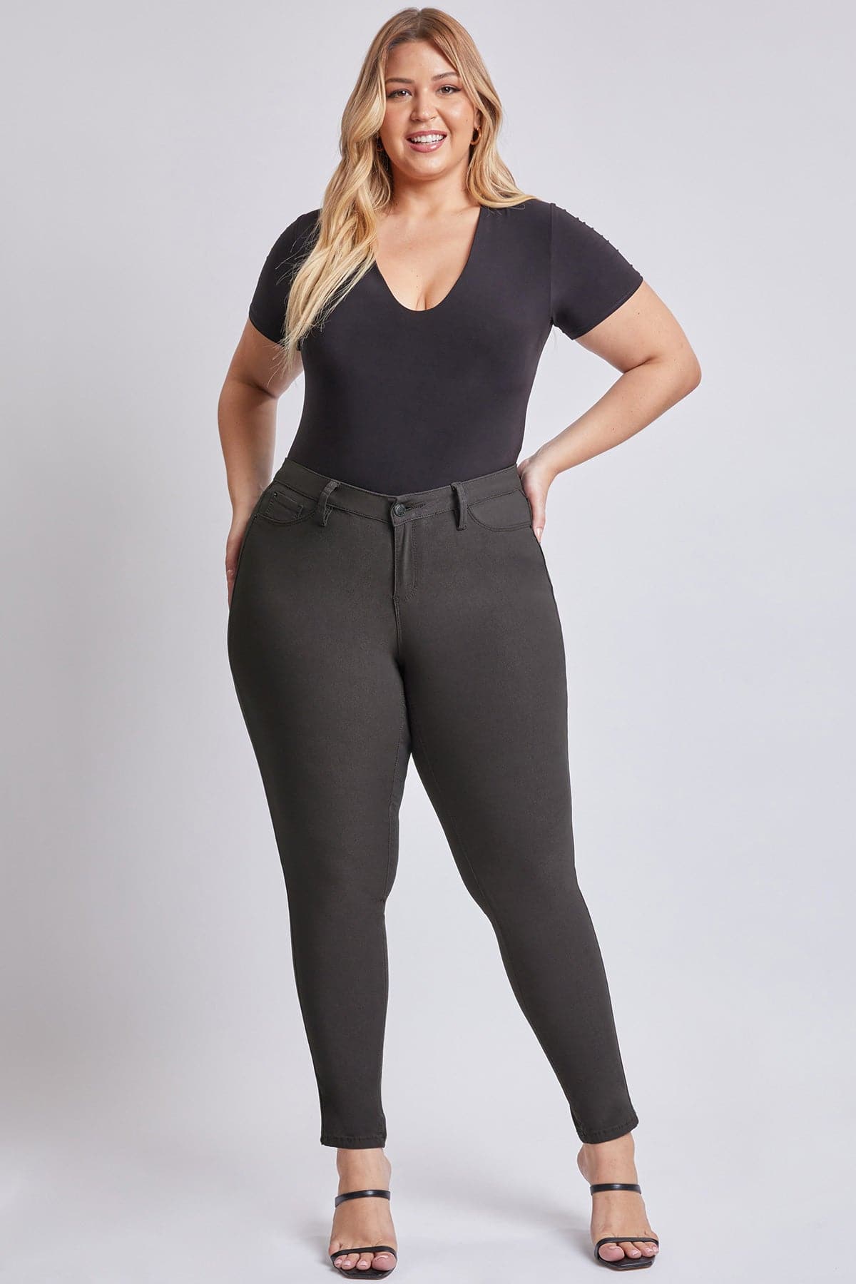 Woman wearing a black bodysuit and gray pants on a white background