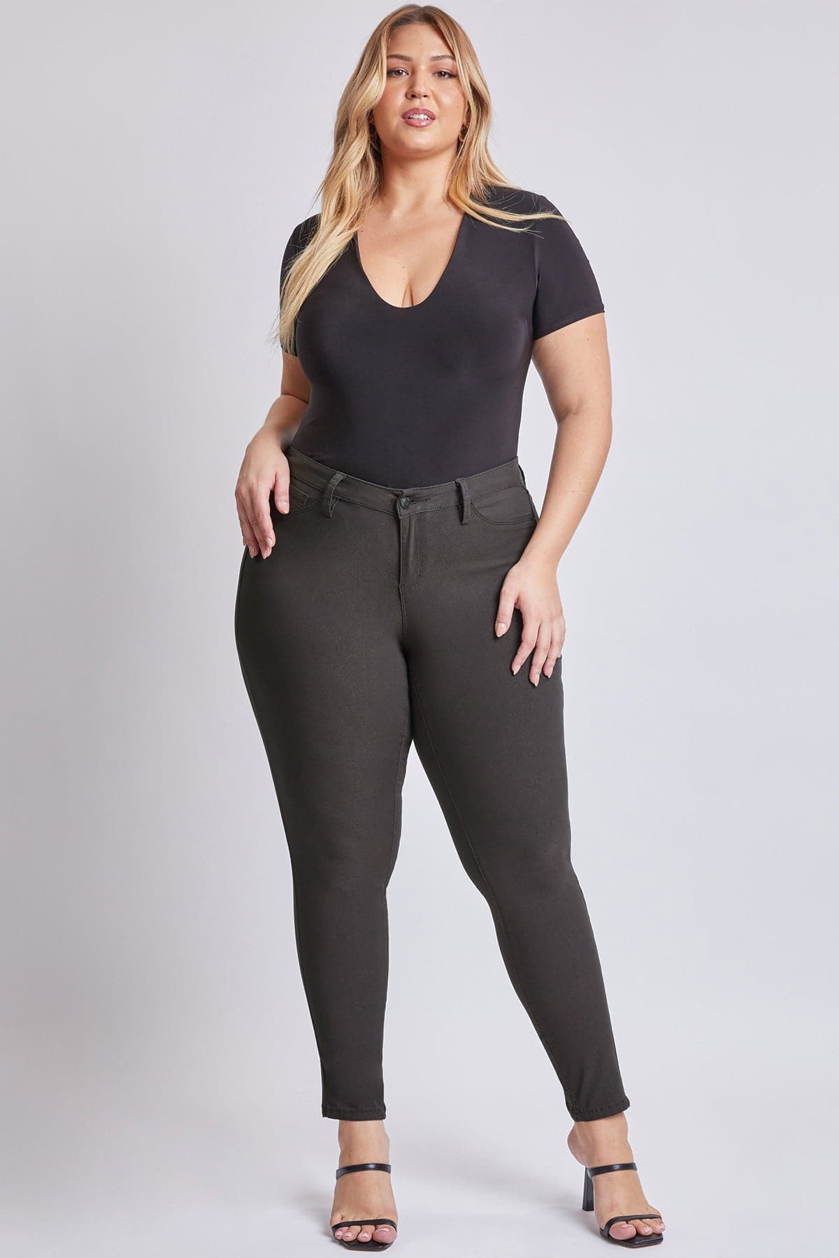 Woman wearing a black bodysuit and gray pants on a white background