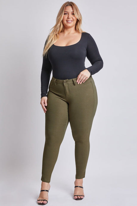 Woman wearing a black long-sleeve top and olive green pants on a white background