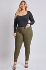 Woman wearing a black long-sleeve top and olive green pants on a white background