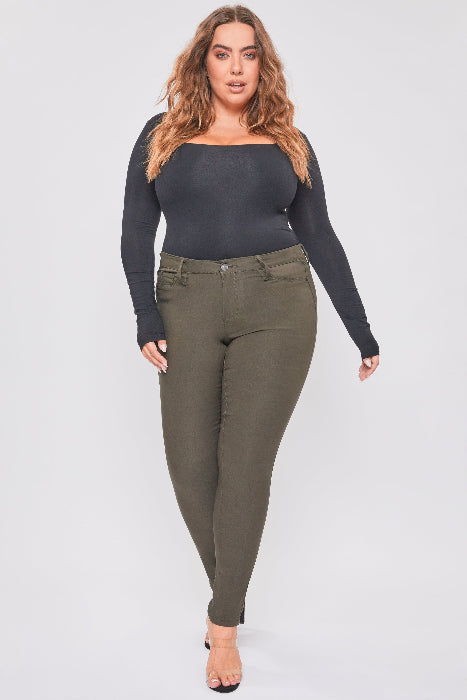 Woman wearing a black long-sleeve top and green pants on a white background