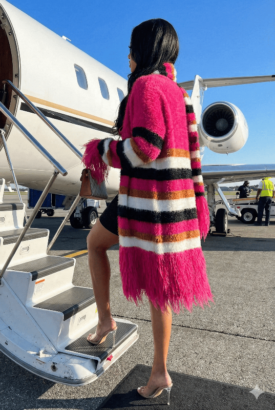 Person in a colorful striped coat stepping off a private jet.