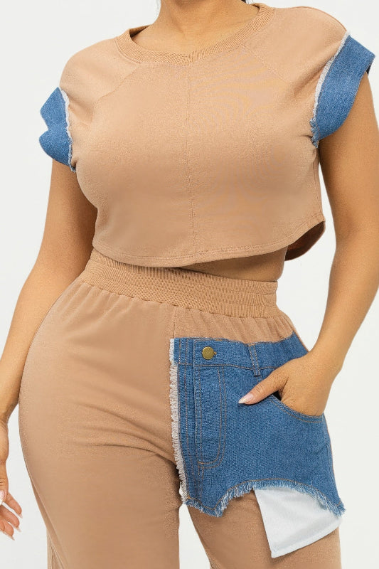 Woman wearing a beige top with blue sleeves and denim accents on a white background