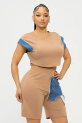 Woman wearing a beige outfit with denim accents on a white background