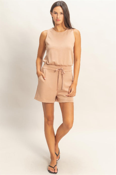 Woman wearing a beige romper on a plain background