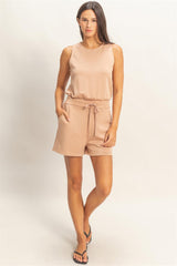 Woman wearing a beige romper on a plain background