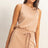 Woman wearing a beige Drawstring Waist Sleeveless Romper on a plain background
