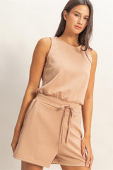 Woman wearing a beige Drawstring Waist Sleeveless Romper on a plain background