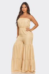 Woman wearing a beige strapless jumpsuit on a white background