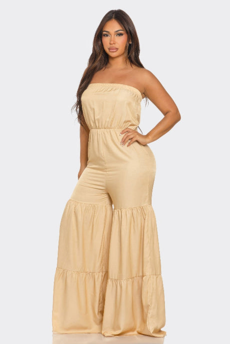 Woman wearing a beige strapless jumpsuit on a white background