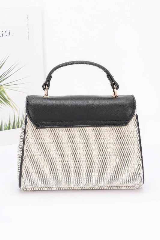 Handbag with black top handle and textured body on a white background