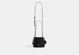 Black Coach Faye Mini handbag with a chain strap on a light gray background