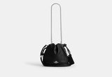 Black Coach Faye Mini handbag with chain strap on a white background