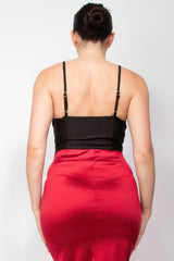 Back view of a woman wearing a black top and red skirt on a white background